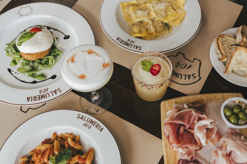 Northern Italian table spread at Salumeria 104 — pasta, salumi, wine, antipasti